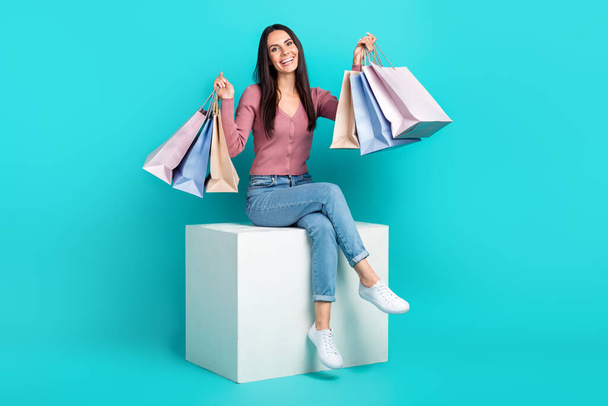 Full body cadre of sit white platform girl raise hands up hold much packages with brand clothes shopaholic isolated on aquamarine color background. - Foto, afbeelding