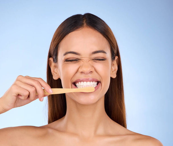 Diş fırçası, diş macunu ve temizlikçi bir kadınla stüdyoda ağız temizliği için mavi arka planda. Ağız, dişçi ve dişleri sağlıklı diş etleri için dişlerini fırçalayan çekici genç bir kadın.. - Fotoğraf, Görsel