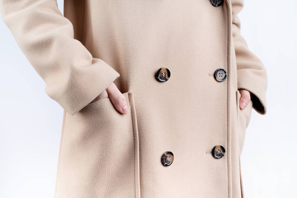 detailní záběr žena v béžovém kabátu výběru oblečení dresing na bílém pozadí. Výběr šatníku, stylistky, nakupování. - Fotografie, Obrázek