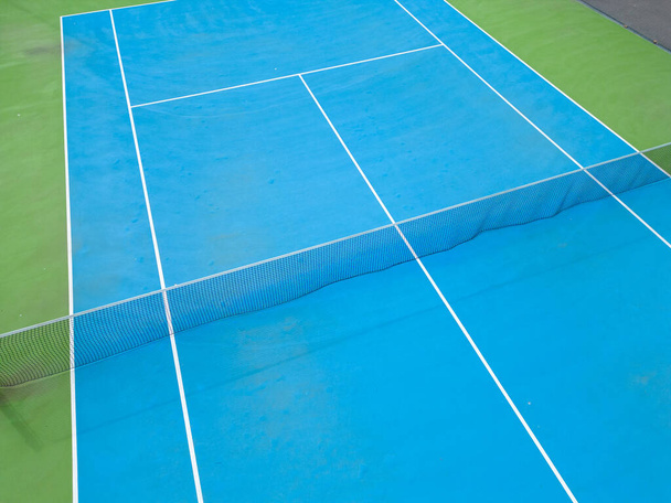 aerial view of a serene blue-green tennis court in an empty state, highlighting the courts well-manicured surface and the lines that mark it - Foto, Bild