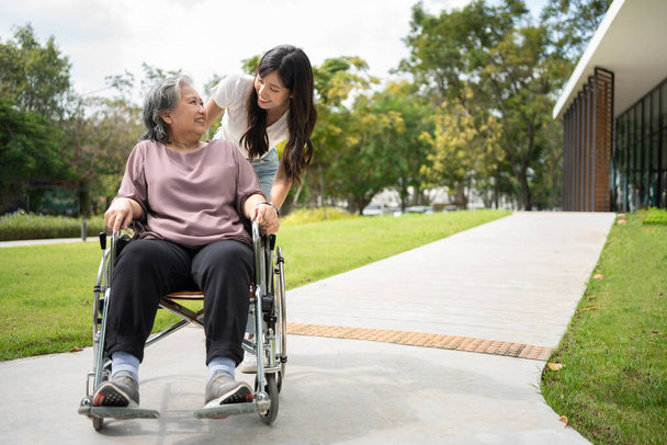 Asiatique soignant soignant soignant ou infirmier prenant soin du patient en fauteuil roulant. Concept de retraite heureuse avec les soins d'un soignant et de l'épargne et de l'assurance-maladie des aînés, une famille heureuse - Photo, image