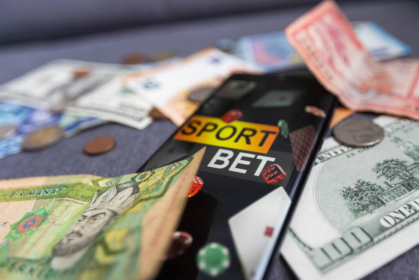 δολάρια και ευρώ, smartphone με εφαρμογή αθλητικών στοιχημάτων. - Φωτογραφία, εικόνα