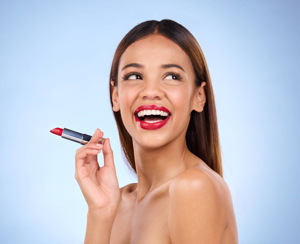 Beauty, red lipstick or makeup with woman thinking about face cosmetics in studio. Aesthetic female model on a blue background think and laugh about product color application idea for lips and skin. - Φωτογραφία, εικόνα