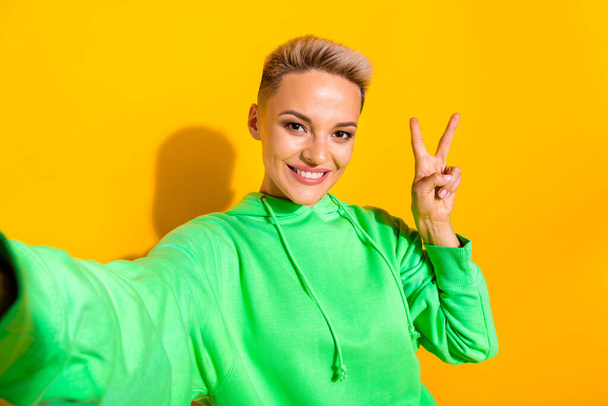 Portrait of gorgeous satisfied person toothy smile make selfie demonstrate v-sign isolated on yellow color background. - 写真・画像