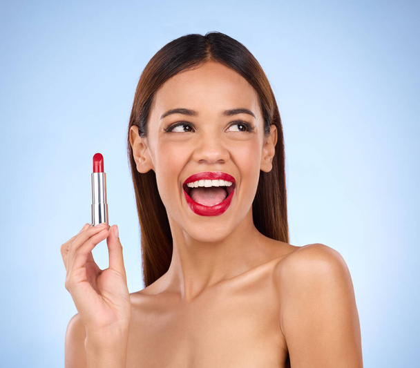Beauty, red lipstick and makeup of woman thinking about skincare or cosmetics promotion in studio. Excited female model on a blue background for self care, facial glow and skin with product color. - Photo, Image