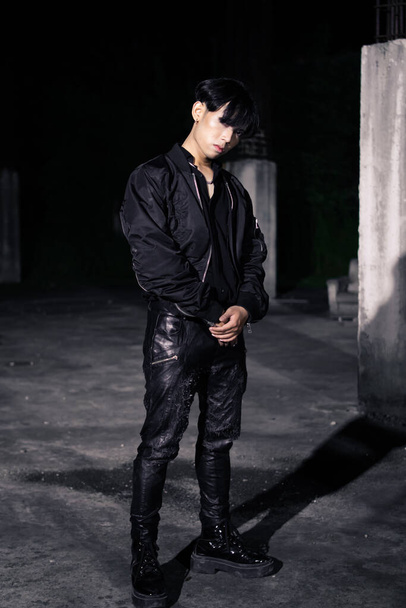 ein asiatischer Mann in schwarzer Fallschirmjacke posiert nachts sehr männlich in einem Gebäude - Foto, Bild