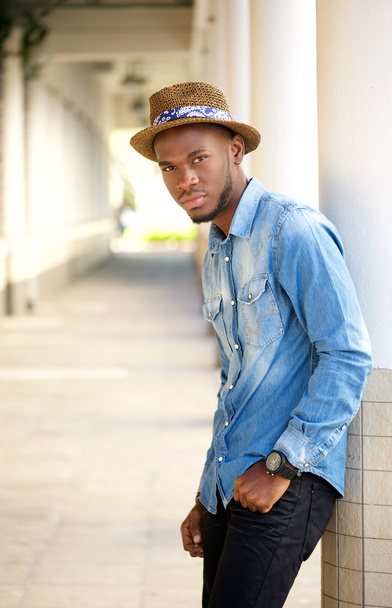 Relaxed young man with hat leaning on wall outdoors - Photo, Image