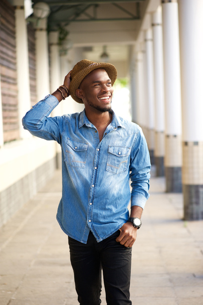 Onnellinen nuori afrikkalainen amerikkalainen mies kävelee hattu päässä
 - Valokuva, kuva