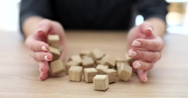 Les mains de la femme versent des cubes de bois sur la table. Jeu et puzzles logiques pour la logique - Séquence, vidéo
