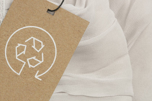 リサイクルアイコンで衣類のタグを閉じます。リサイクル製品のコンセプト。廃棄物ゼロ、持続可能な生産、環境への配慮と再利用の概念. - 写真・画像