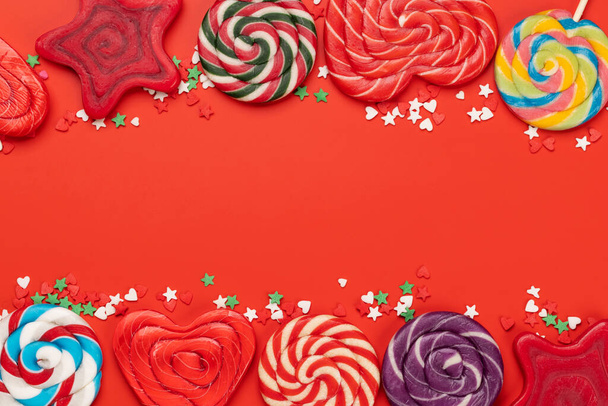 Various candy sweets and lollipops on red background and copy space for your text. Flat lay - Photo, Image
