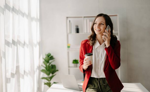 Businesswoman Talking on the phone with coffee at home office - Photo, Image