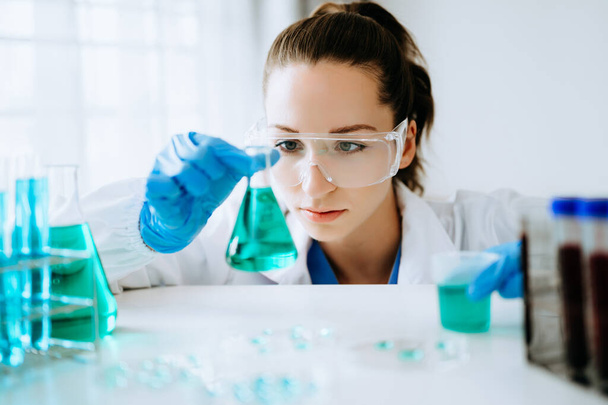 Female scientist researcher conducting an experiment in the chemical laboratory - Foto, immagini