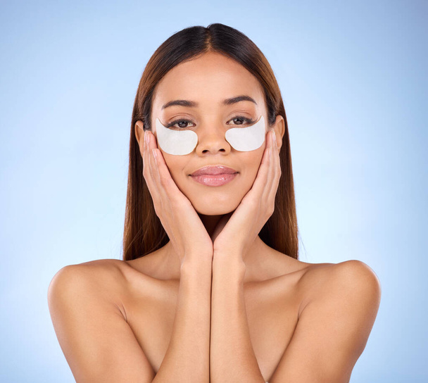 Beauty, collagen and portrait of woman with eye mask for anti aging skincare glow on blue background. Cosmetics, facial repair and face of hispanic model with wrinkle treatment product in studio - Zdjęcie, obraz