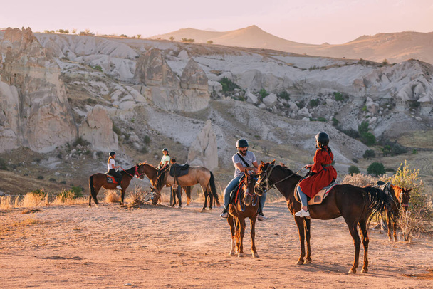 12 September 2022, Cappadocia, Turkey: Group of tourists riding horses during excursion at sunset - Photo, Image
