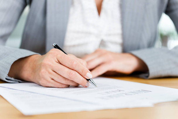Close-up shot of businesswoman filling out insurance policy in her office - Foto, Imagem