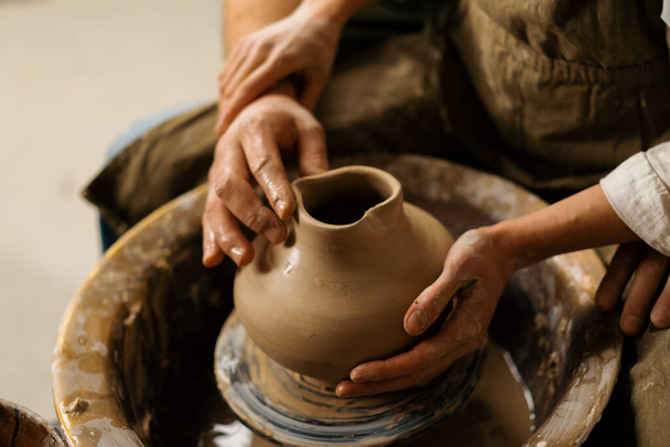 Taller de cerámica un alfarero enseña a los estudiantes a esculpir jarra de arcilla pareja se dedica a la cerámica - Foto, imagen