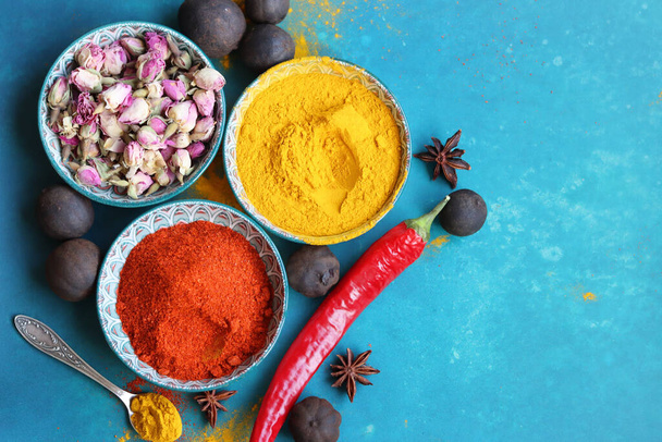 Colorful still life with three ceramic bowls full of spices. Turmeric, paprika powder, dried roses, anise close up photo. Indian culture concept.  - Photo, Image