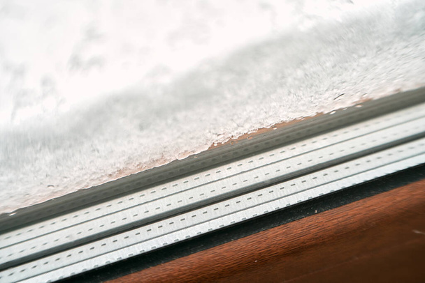bruin PVC raam close-up tijdens sneeuwbuien. gezellig binnen beschermd met goede kwaliteit ramen terwijl warme lucht in het huis. PVC met driedubbel glas - Foto, afbeelding