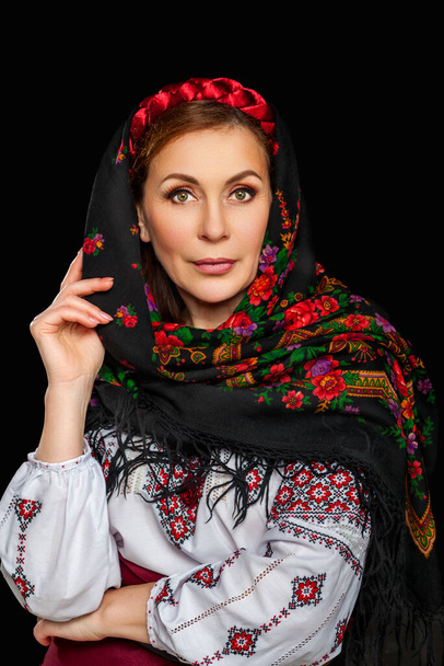 Beautiful Ukrainian woman in national costume. Attractive Ukrainian woman wearing in traditional Ukrainian embroidery, isolated at black background. - Foto, afbeelding
