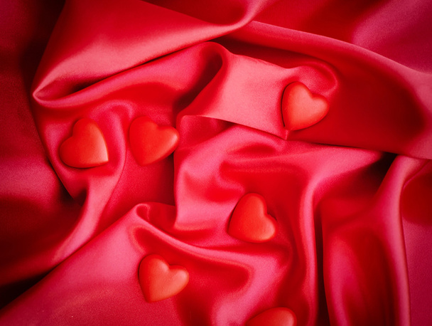 Red hearts on satin fabric background - Photo, image