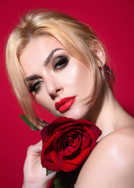 Bright make-up. Red lips with red lipstick. Fashion portrait of young beautiful lady with flowers. Portrait of elegant beautiful woman with naked shoulder hold rose flower, isolated on studio - Photo, image