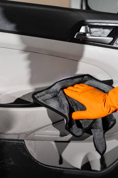 El secado interior del coche de la mano del panel de la tarjeta de la puerta del coche usando microfibra en el servicio auto que detalla. Trabajador más limpio coche seco interior - Foto, Imagen