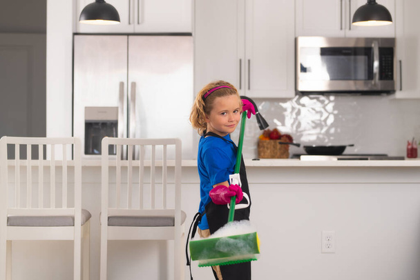 Dziecko sprząta w domu. Dzieciak sprzątanie mopem, aby pomóc w pracach domowych. Little cute boy zamiatanie i sprzątanie, na tle kuchni - Zdjęcie, obraz