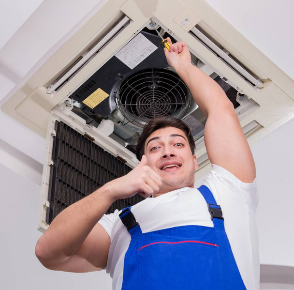 Le travailleur réparer l'unité de climatisation de plafond - Photo, image