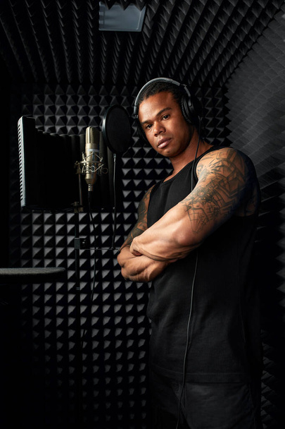 African American at the recording studio in headphones reads rap. - Zdjęcie, obraz