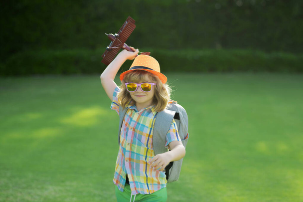 Kid having fun with toy airplane in field. Child pilot aviator with airplane dreams of traveling in summer in nature - Photo, image