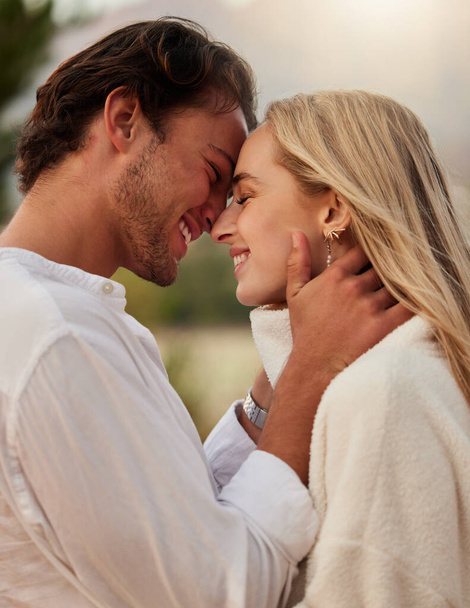 Love, care and kiss with couple in nature for romance, bonding and affectionate together. Close, happiness and embrace with man and woman hugging on date for sunset, anniversary and summer break. - Valokuva, kuva