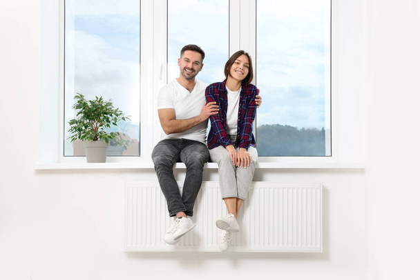 Happy couple sitting on windowsill in new apartment. Moving day - Fotoğraf, Görsel