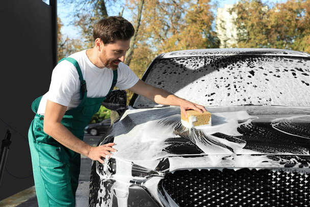 Worker washing auto with sponge at outdoor car wash - Zdjęcie, obraz