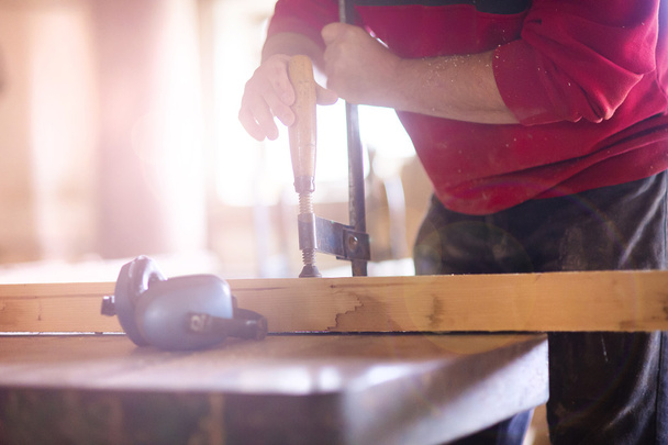 Carpenter screwing a glue clamp - Foto, imagen