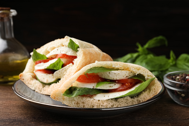 Delicious pita sandwiches with mozzarella, tomatoes and basil on wooden table, closeup - Φωτογραφία, εικόνα