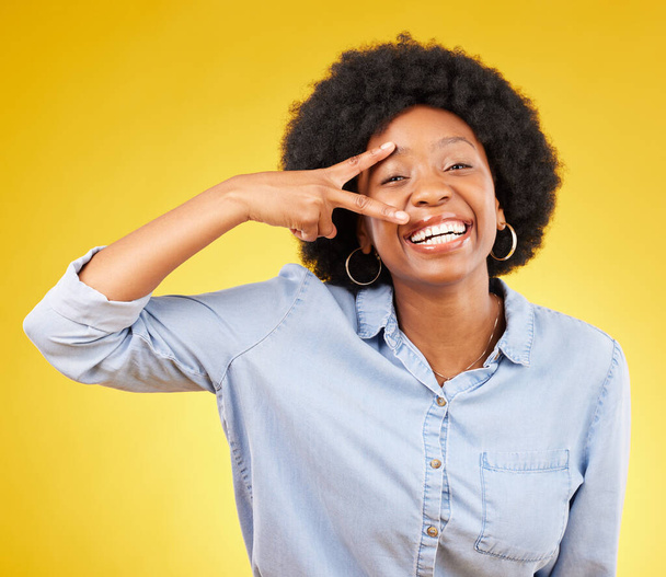 Black woman, peace sign and smile portrait in studio while happy on yellow background. African female model with hand gesture or emoji while laughing on color with motivation and positive mindset. - Valokuva, kuva