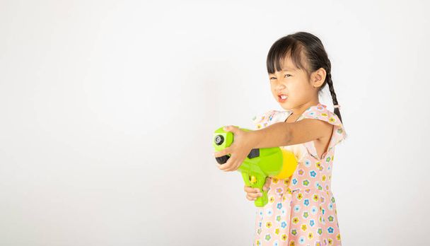 Happy Songkran Day, Asian little girl holding plastic water gun, Thai child funny hold toy water pistol and smile, isolated on white background, Thailand Songkran festival national culture concept - Zdjęcie, obraz