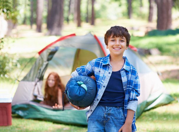 Reclamando su lugar de acampada. Un chico parado frente a su campamento - Foto, imagen