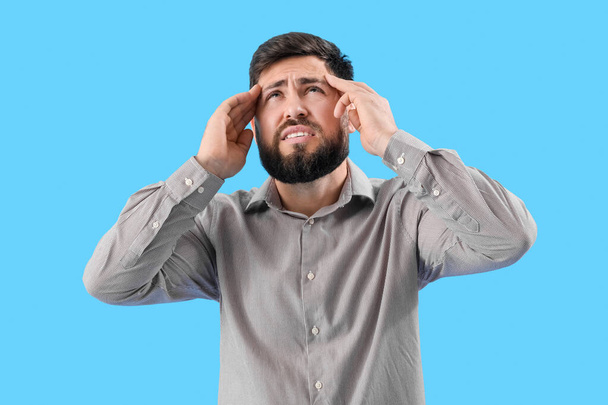 Young man suffering from loud noise on blue background - Foto, immagini