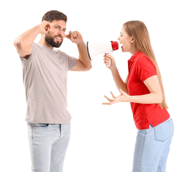 Mujer joven con megáfono gritándole a su marido sobre fondo blanco - Foto, Imagen