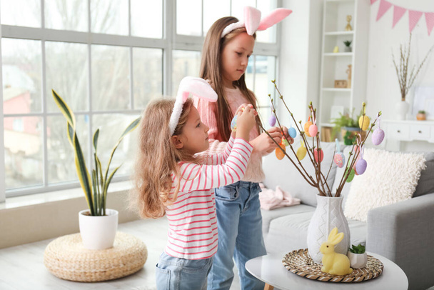 Kislányok díszítik fa ágak húsvéti tojás otthon - Fotó, kép