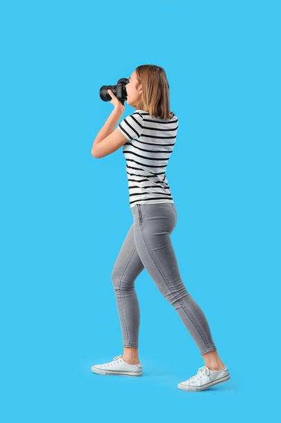 Fotógrafo femenino con cámara profesional sobre fondo azul - Foto, imagen