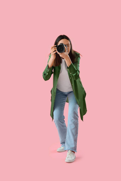Photographe femelle avec appareil photo professionnel sur fond rose - Photo, image