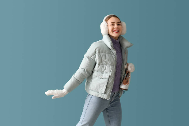 Pretty young woman with ice skates on blue background - Foto, Bild