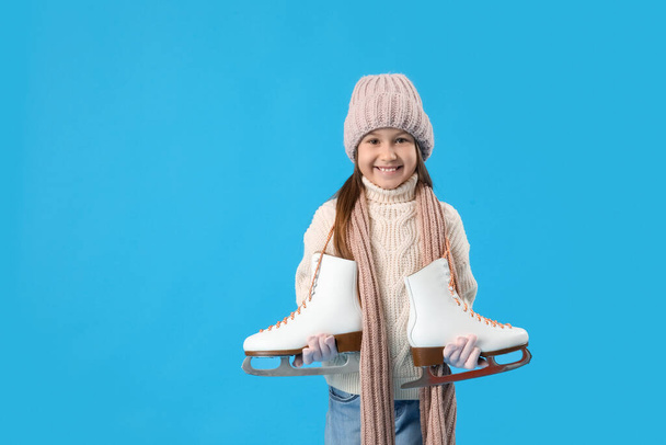Little girl in winter clothes with ice skates on blue background - Foto, Bild