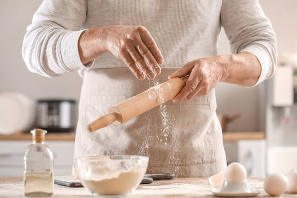 Чоловічий шеф-кухар робить тісто для макаронних виробів за столом на кухні, крупним планом
 - Фото, зображення