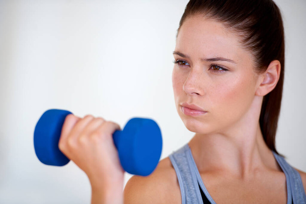 Determined to get fit. An attractive young woman training with dumbbells and looking confident - Foto, Imagem