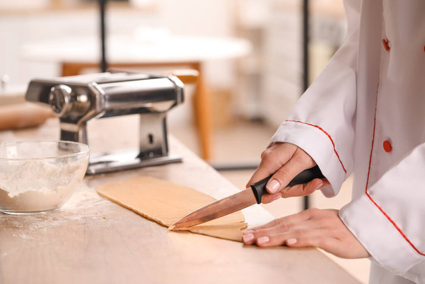 Female chef making pasta with machine at table in kitchen, closeup - Photo, Image
