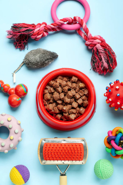Composición con tazón de comida húmeda y diferentes accesorios para el cuidado de mascotas sobre fondo de color - Foto, Imagen